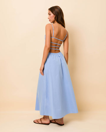 Woman wearing a light blue dress with thin straps on a beige background